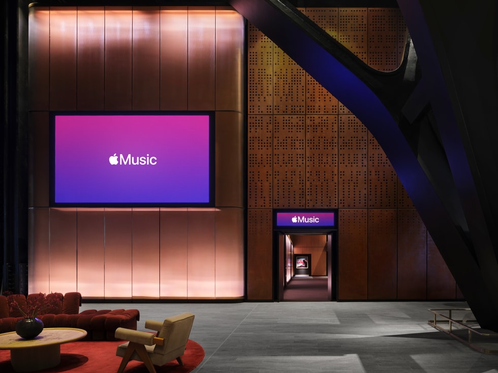 Apple Music Hall fuayesi: tuğla duvarda büyük bir ekranda mevcut Apple Music logosu, önde oturma alanı