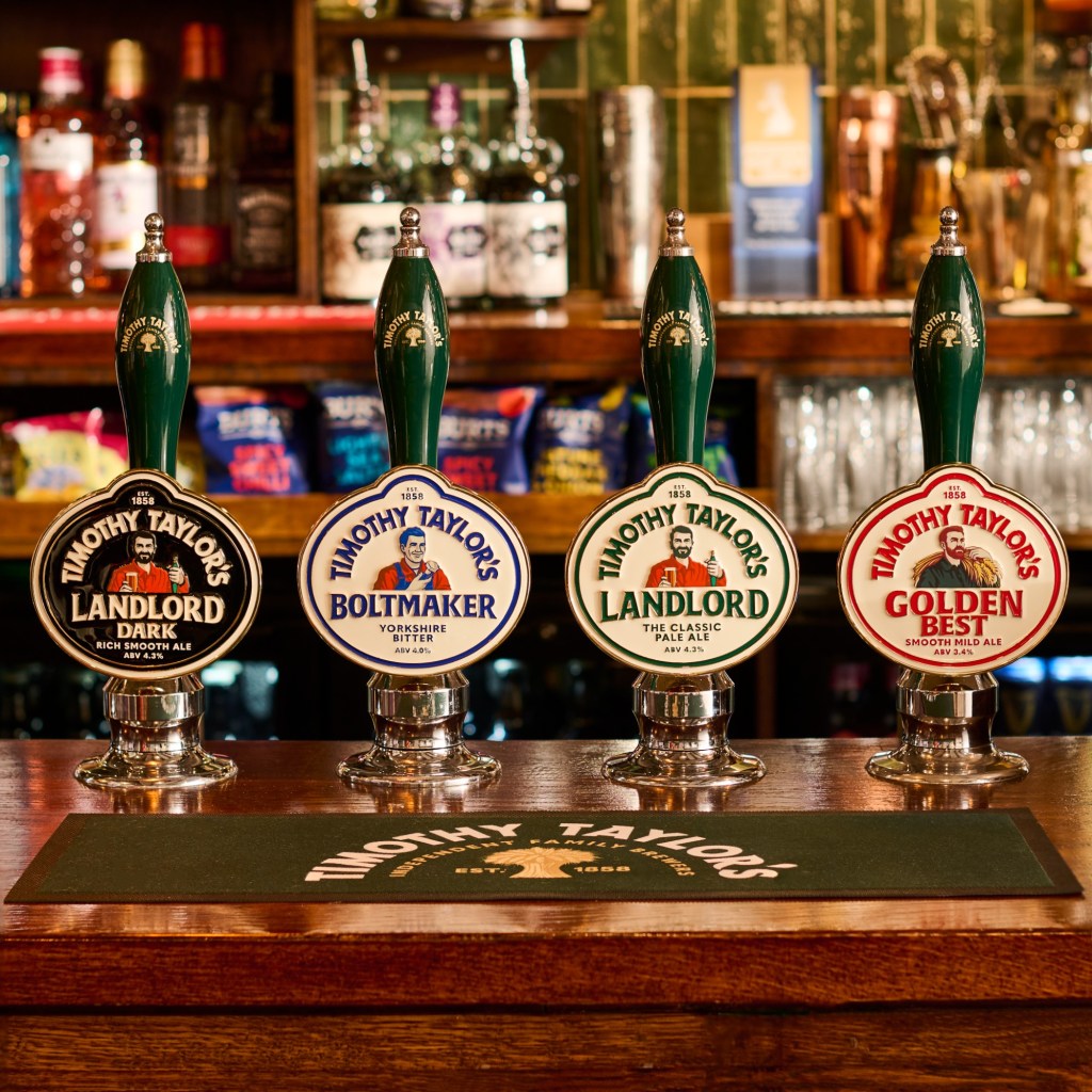 Bir bar tezgahında koyu yeşil kollu dört bira pompası; Landlord Dark, Boltmaker, Landlord ve Golden Best'in yeni oval pompa etiketleri